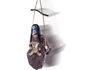 Een aan een touw gehangen Schommelend Meisje met een beer op schoot.